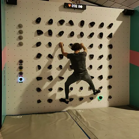 Grimpeur sautant sur le mur interactif Luxov avec le score affiché en direct à Arcabloc Vichy